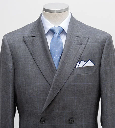 Mannequin wearing grey blazer and vest, white shirt, blue tie, and white pocket square.