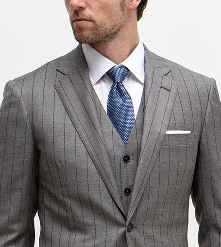 Model wearing grey blazer with thin black vertical stripes, matching vest, white shirt, and light blue tie.