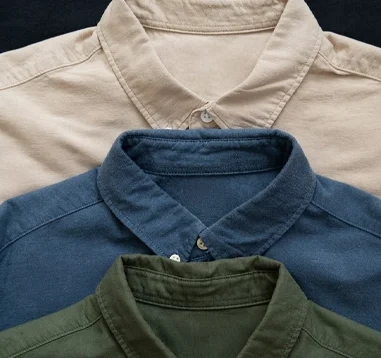 Stack of beige, navy blue, and olive green button-down shirts representing casual and elegant menswear.