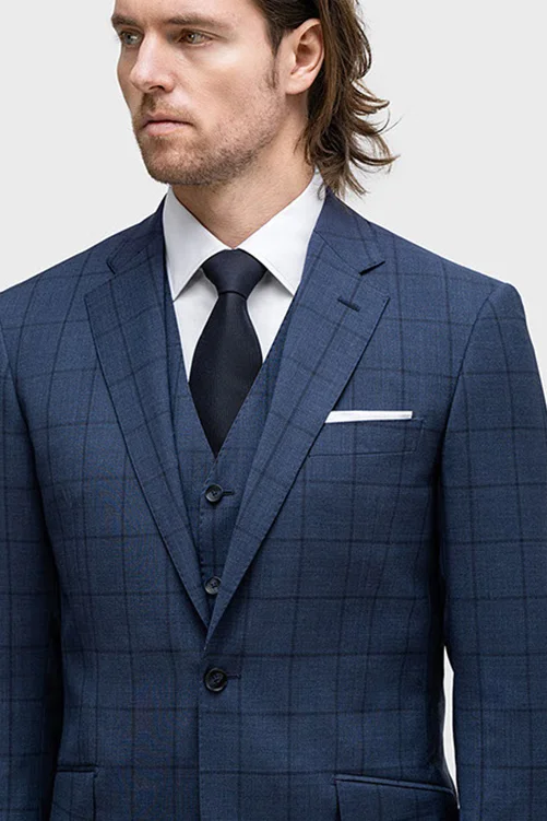 Model in a navy suit with darker windowpane pattern, white shirt, and navy tie; partial body visible.