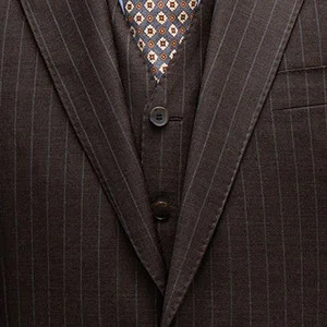 Close-up of a brown suit with a vest and beige-patterned tie.