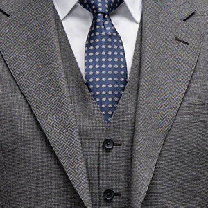Close-up of a gray suit with vest, white shirt, and dark blue tie.